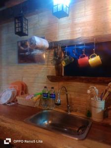 a kitchen counter with a sink with cups and bottles at Cabaña en el Arbol Picasso in Bogotá