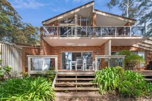 a brick house with a balcony and stairs at Denhams Beach Waterfront in Surf Beach