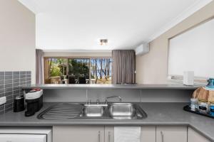a kitchen counter with a sink and a window at Denhams Beach Waterfront in Surf Beach
