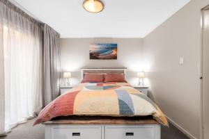 una camera da letto con un letto con un piumone colorato di Denhams Beach Waterfront a Surf Beach