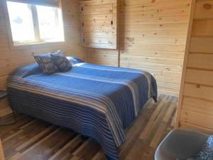 ein Schlafzimmer mit einem Bett in einer Holzhütte in der Unterkunft Sonny’s in Keene
