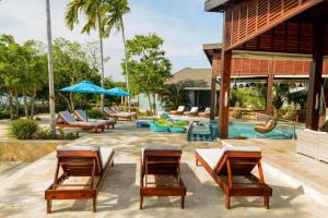 a patio with tables and chairs and a pool at The Enclave - Your Own Private Island Retreat in Placencia Village