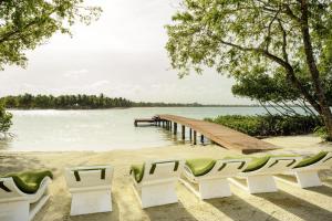 a beach with chairs and a dock and water at The Enclave - Your Own Private Island Retreat in Placencia Village