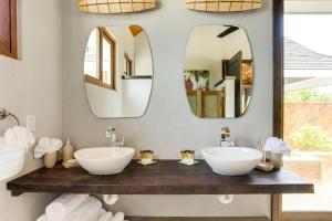 two sinks in a bathroom with two mirrors at The Enclave - Your Own Private Island Retreat in Placencia Village