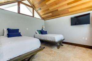 a bedroom with two beds and a flat screen tv at The Enclave - Your Own Private Island Retreat in Placencia Village