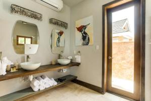 a bathroom with two sinks and two mirrors at The Enclave - Your Own Private Island Retreat in Placencia Village