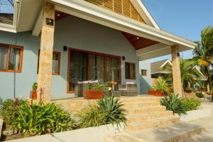 a home with a porch with plants and stairs at The Enclave - Your Own Private Island Retreat in Placencia Village