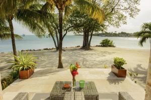 a table with a vase of flowers on the beach at The Enclave - Your Own Private Island Retreat in Placencia Village