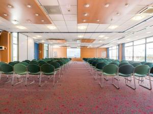 une salle de conférence avec des chaises vertes et un écran dans l'établissement ibis Paris 17 Clichy-Batignolles, à Paris