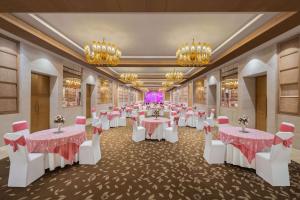 un salón de banquetes con mesas y sillas blancas y lámparas de araña en Radisson Blu Hotel New Delhi Dwarka en Nueva Delhi