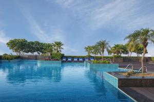 a swimming pool with blue water and palm trees at Radisson Blu Hotel New Delhi Dwarka in New Delhi