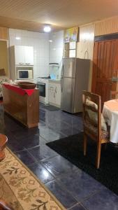 cocina con nevera, mesa y silla en Cabañas Lomas del llaima, en Melipeuco