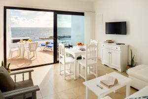 a living room with a table and a kitchen with a view of the ocean at Delmar Natur - Sama in Charco del Palo