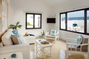un soggiorno con mobili bianchi e vista sull'oceano di Delmar Natur - Cherne a Charco del Palo