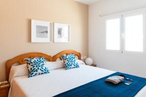 Un dormitorio con una cama con almohadas azules y blancas. en Delmar Natur - Gallo, en Charco del Palo