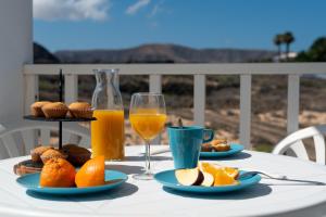 una mesa con platos de comida y dos vasos de zumo de naranja en Delmar Natur - Gallo, en Charco del Palo