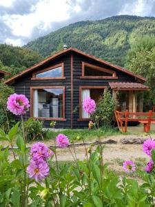 a log cabin with pink flowers in front of it at CABAÑAS RUCA MALAL in Futrono