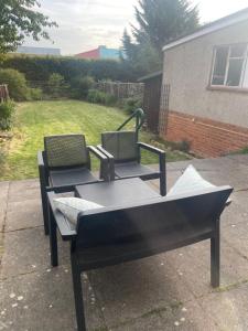 two chairs and a barbecue grill in a yard at Wardown Place - Spacious 3 Bed House available for short term or long term Rental in Luton