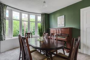 a dining room with a table and a piano at Charming 3BD Home Didsbury House in Manchester