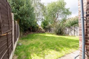 een achtertuin met een hek en groen gras bij Charming 3BD Home Didsbury House in Manchester