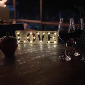 two glasses of wine on a table with a sign with the word love at posada sunrise view vacation home in Providencia
