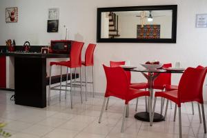 a kitchen with red chairs and a table with a mirror at Casa Aurora in Cancún