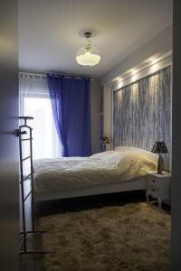 ジブヌベクにあるBaltic View Apartmentのベッドルーム1室(紫色のカーテンと窓付きのベッド1台付)