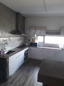 uma cozinha com armários brancos e um lavatório em PREM VILLA em Petit Raffray