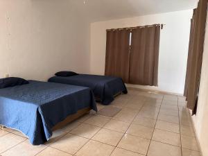 a bedroom with two beds and a tiled floor at Los toronjos in Tequila