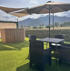 a table and chairs with an umbrella on the grass at Los toronjos in Tequila