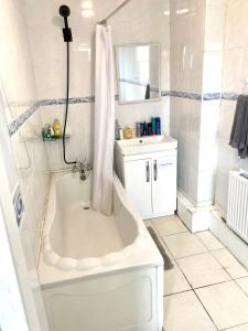 a white bathroom with a tub and a sink at Elegant single-occupancy double bed room(1 person only) in Morriston