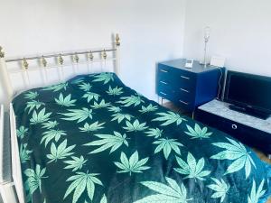 a bedroom with a bed with a green leaf bedspread at Elegant single-occupancy double bed room(1 person only) in Morriston