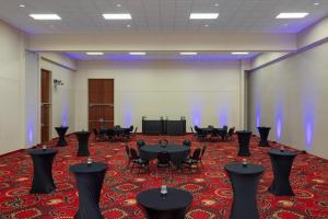 una sala de conferencias con mesas, sillas y una pantalla en Holiday Inn Des Moines-Airport Conf Center, an IHG Hotel, en Des Moines