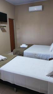 twee bedden in een hotelkamer met een tv bij Sítio Rupestre - Peruaçu in Januária
