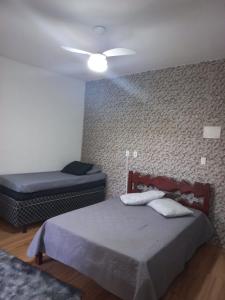 1 dormitorio con 2 camas y ventilador de techo en Kitnet Arraial do Cabo, Monte Alto. en Arraial do Cabo
