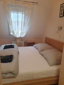 1 dormitorio con 1 cama con sábanas blancas y ventana en Szófia Wellness Apartman, en Nagykanizsa