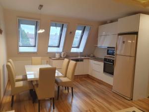 a kitchen with a table and chairs and a refrigerator at Szófia Wellness Apartman in Nagykanizsa