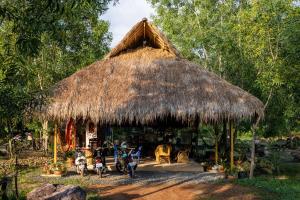 a hut with a thatched roof with animals in it at Kampot Camping in Kampot