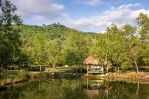 贡布Kampot Camping - Eco Retreat的一座小屋，旁边是水体和一座山