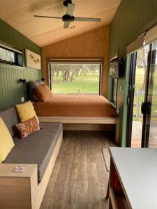 a bedroom in a tiny house with a bed and a window at Marlo Hideaway in Marlo