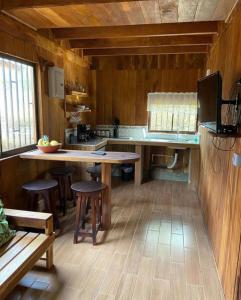 una cocina con mesa y taburetes. en Cabañas El Okaso del Sol, en Santa Cruz