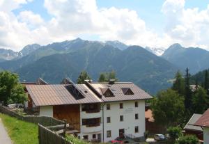 a white building with mountains in the background at Pension Alpenrose in Serfaus