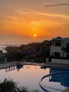 um pôr-do-sol sobre o oceano com uma piscina em Appartement vue sur mer em Agadir