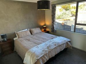 a bedroom with a bed and a large window at Streamside Family Friendly Oasis with Spa in Rotorua