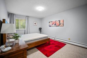 a bedroom with a bed and a desk and a red rug at CHIC 2BR Near Keyano College Free Parking in Fort McMurray