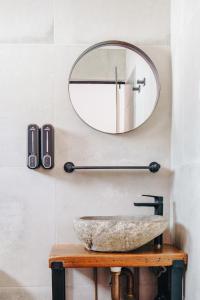 a bathroom with a round mirror and a stone sink at The Pink Hotel Coolangatta in Gold Coast