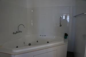 a white bathroom with a tub and a shower at Waves Motel and Apartments in Warrnambool