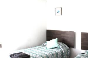 a small bedroom with a bed and a headboard at Grandioso departamento a cuadras de Parque O'higgins in Santiago
