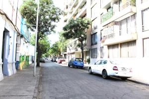 una calle con dos coches estacionados en el lateral de un edificio en Grandioso departamento a cuadras de Parque O'higgins, en Santiago