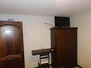 a room with a desk and a cabinet and a television at HOTEL en el CENTRO HISTORICO in Cuenca